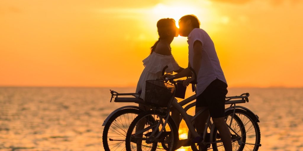 two people having a date and riding a bicycle in the sunset