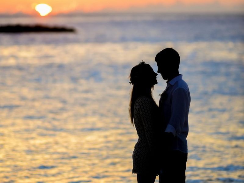 two people falling in love unexpectedly in front of a hawaiian sunset